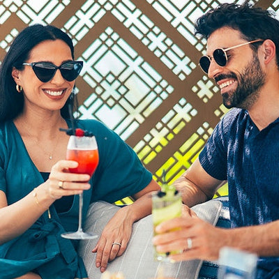 Two people enjoying cocktails together with a decorative background